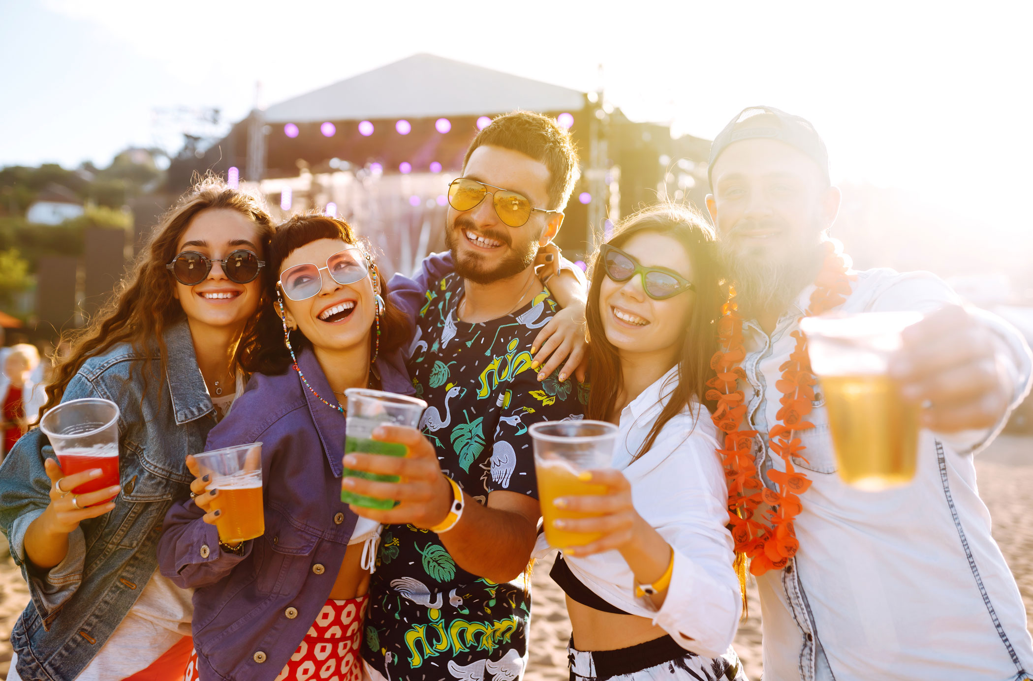 Young happy friends drinking beer and having fun at music festival